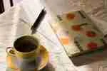 Cup of black coffee and a notebook on a newspaper in warm morning light