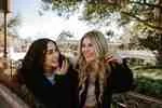 Two women friends laughing together on a bench outdoors